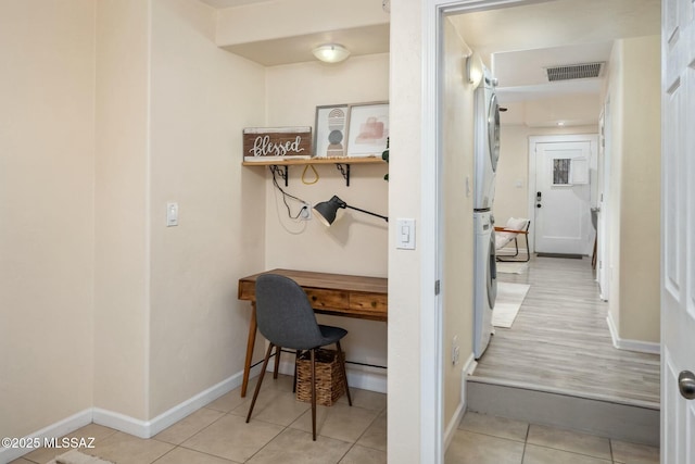 tiled home office featuring stacked washing maching and dryer