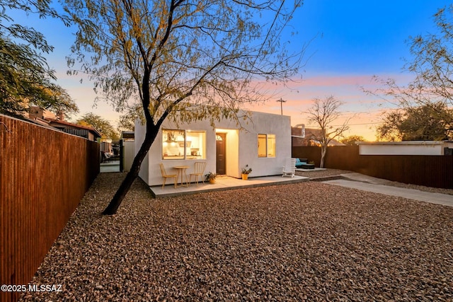 back house at dusk featuring a patio area