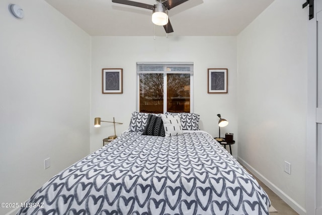 bedroom with ceiling fan and a barn door