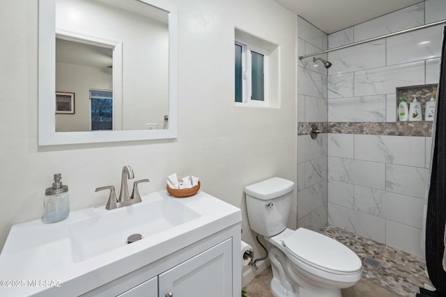 bathroom with vanity, toilet, and tiled shower