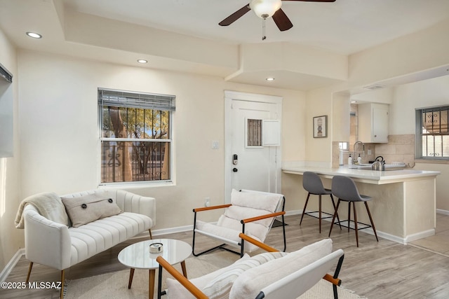 living room with ceiling fan, sink, and light hardwood / wood-style floors