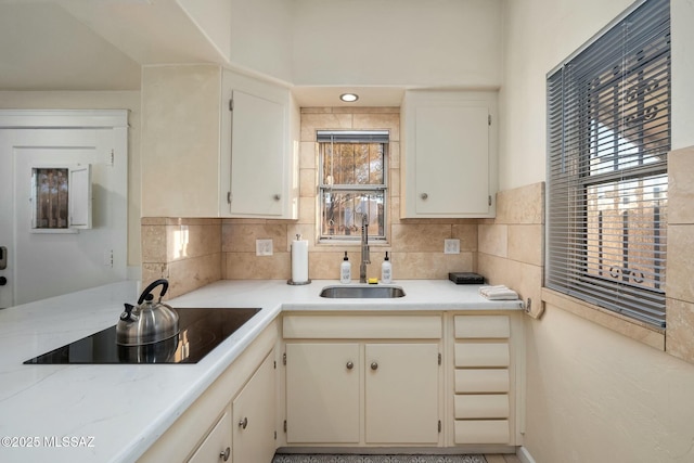 kitchen featuring black electric cooktop, sink, and decorative backsplash