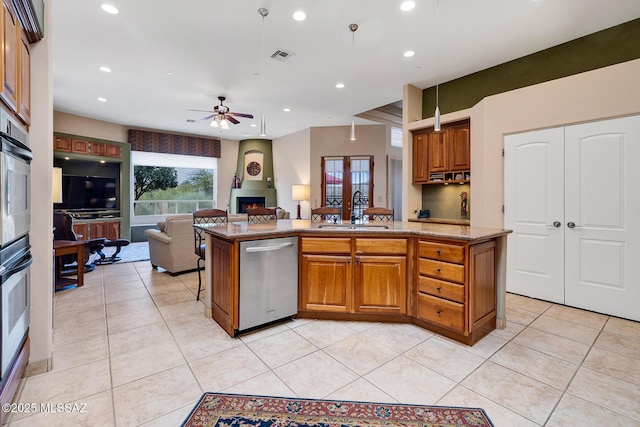 kitchen featuring stainless steel dishwasher, a center island, sink, and a large fireplace