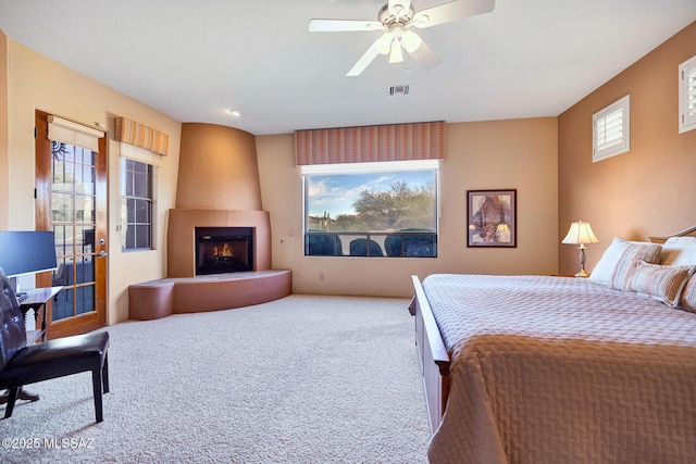 bedroom featuring ceiling fan, a fireplace, and carpet