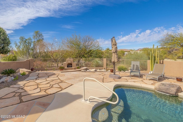 view of swimming pool featuring an outdoor fireplace and a patio area