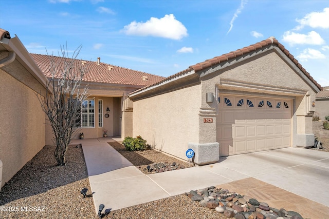 view of front facade with a garage, driveway, a tiled roof, and stucco siding