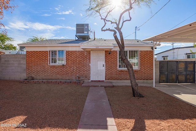 view of front facade featuring central air condition unit, brick siding, and fence