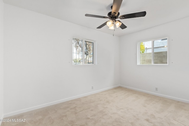 empty room with baseboards, light colored carpet, and a ceiling fan