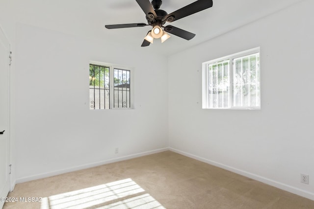 empty room featuring baseboards, light colored carpet, and a ceiling fan