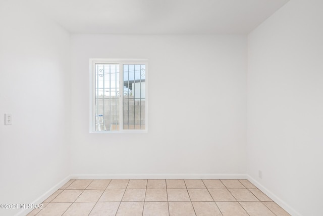 empty room featuring light tile patterned flooring and baseboards