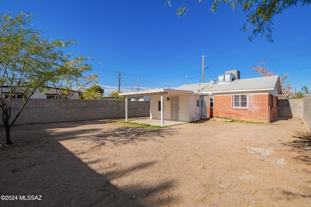 rear view of property with brick siding, a patio area, and a fenced backyard