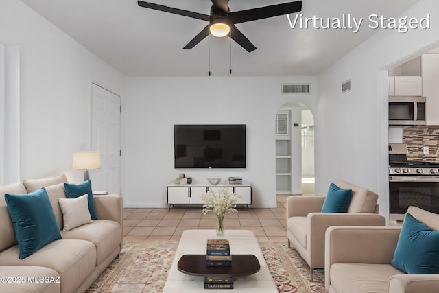 tiled living area featuring visible vents, arched walkways, and a ceiling fan