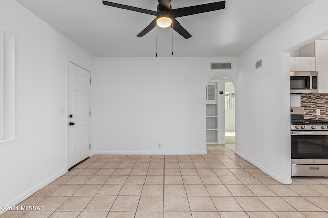 empty room featuring light tile patterned floors, arched walkways, visible vents, and ceiling fan