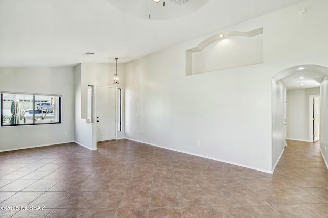 spare room with light tile patterned flooring, ceiling fan, and high vaulted ceiling