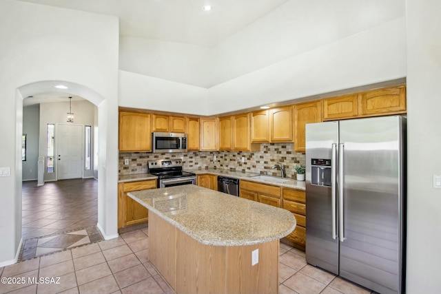 kitchen featuring a kitchen island, appliances with stainless steel finishes, sink, a high ceiling, and light tile patterned floors