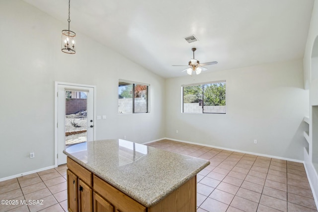 kitchen featuring light tile patterned floors, ceiling fan with notable chandelier, a kitchen island, decorative light fixtures, and vaulted ceiling