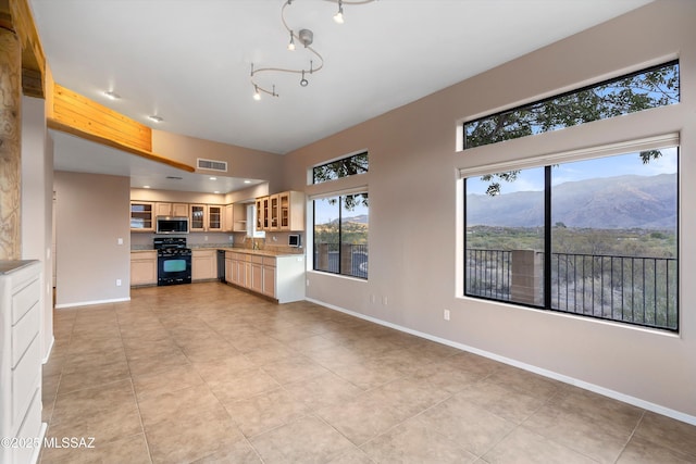 kitchen featuring a mountain view, black appliances, sink, light tile patterned floors, and tasteful backsplash