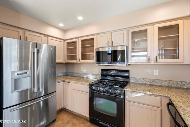 kitchen with light stone countertops, appliances with stainless steel finishes, and light tile patterned flooring