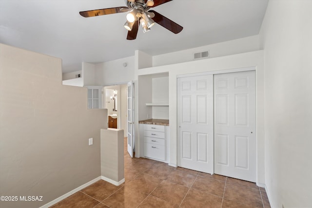 unfurnished bedroom featuring light tile patterned floors, a closet, and ceiling fan