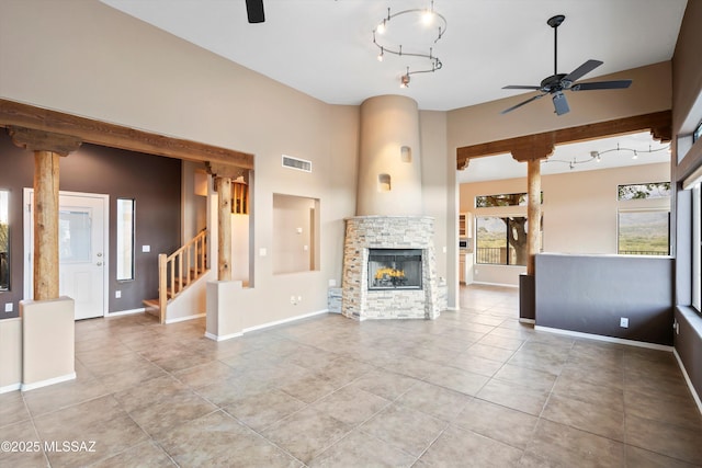 unfurnished living room featuring a stone fireplace, ceiling fan, and light tile patterned flooring