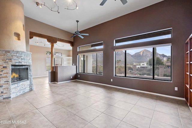 unfurnished living room with a mountain view, light tile patterned flooring, a fireplace, and ceiling fan