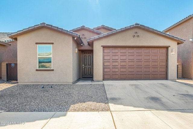 view of front of house featuring stucco siding, a garage, driveway, and a tile roof