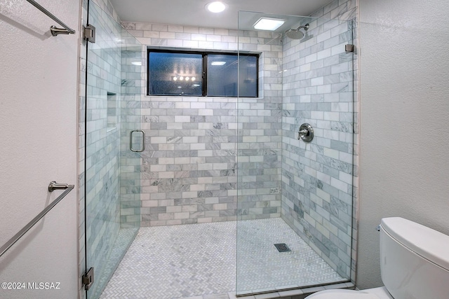 bathroom featuring a shower with door and toilet