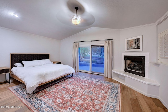 bedroom featuring access to outside, vaulted ceiling, hardwood / wood-style flooring, ceiling fan, and ornamental molding