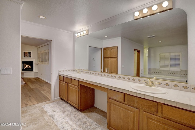 bathroom featuring tile patterned floors, ornamental molding, a washtub, vanity, and a textured ceiling