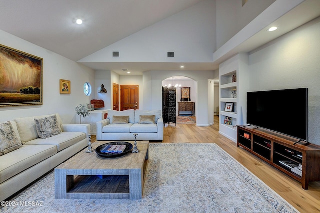 living room featuring built in features, high vaulted ceiling, hardwood / wood-style floors, and an inviting chandelier