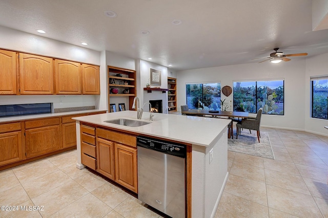 kitchen featuring dishwasher, a kitchen island with sink, sink, light tile patterned floors, and built in features