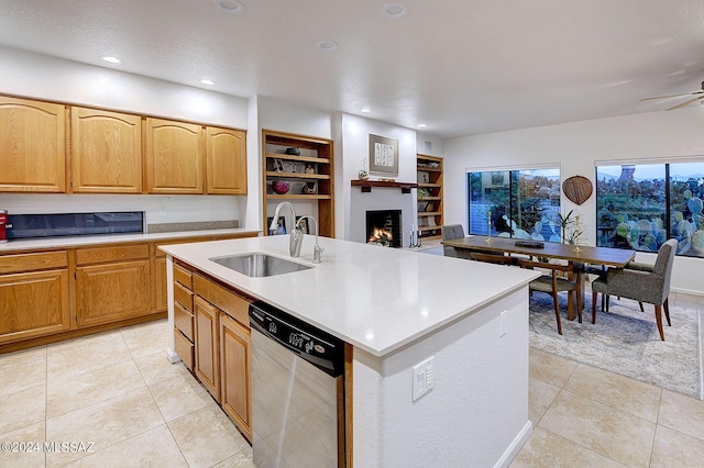 kitchen featuring stainless steel dishwasher, sink, built in features, a fireplace, and an island with sink