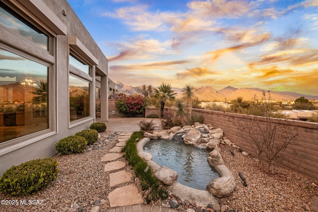 yard at dusk featuring a mountain view and a patio