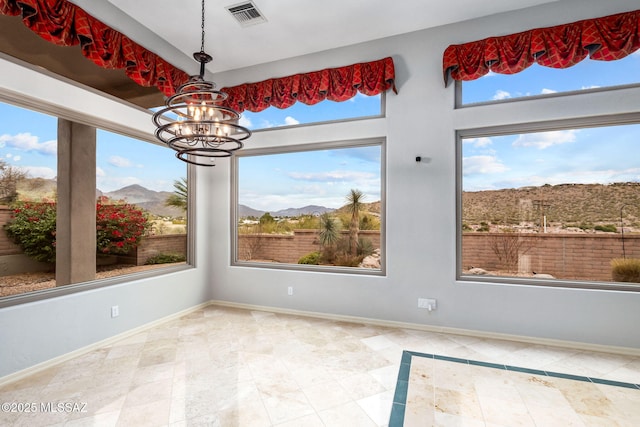 unfurnished dining area featuring a mountain view, plenty of natural light, and a notable chandelier