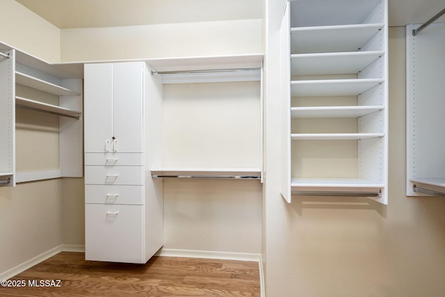 walk in closet with light hardwood / wood-style flooring