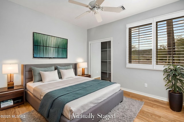 bedroom featuring a walk in closet, light wood-type flooring, a closet, and ceiling fan