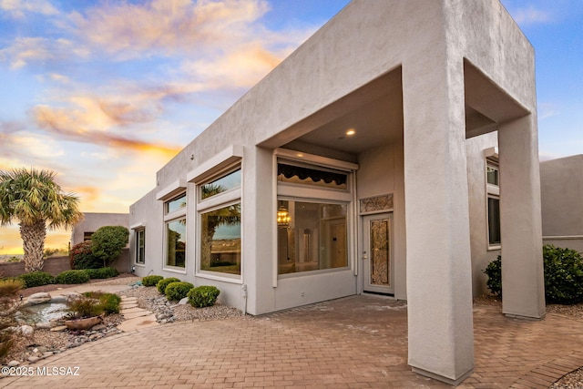 back house at dusk featuring a patio