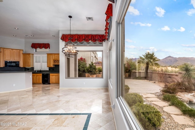 kitchen featuring a mountain view, backsplash, sink, decorative light fixtures, and a notable chandelier