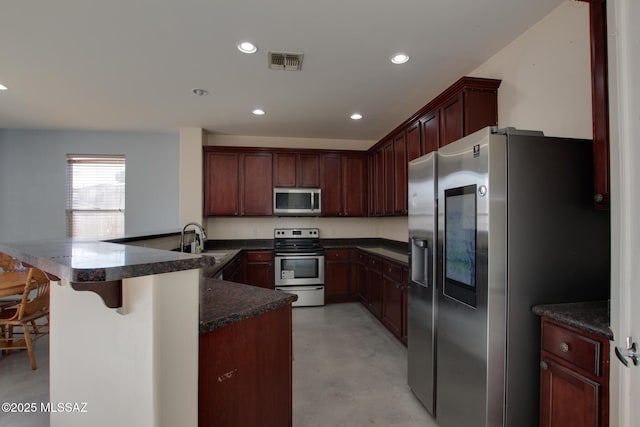 kitchen with stainless steel appliances, sink, a kitchen bar, and kitchen peninsula