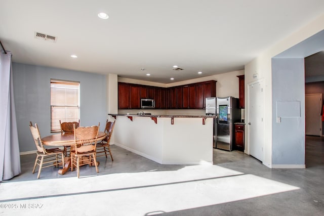 kitchen with a kitchen bar, kitchen peninsula, and appliances with stainless steel finishes