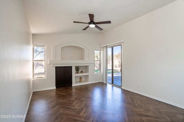 unfurnished living room with dark parquet flooring, a wealth of natural light, and ceiling fan