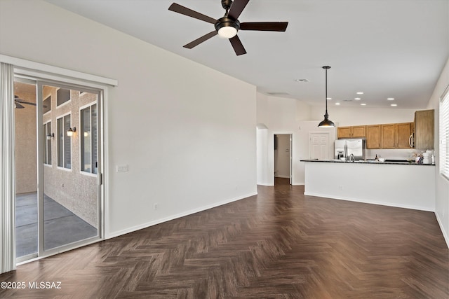 unfurnished living room featuring ceiling fan and dark parquet flooring