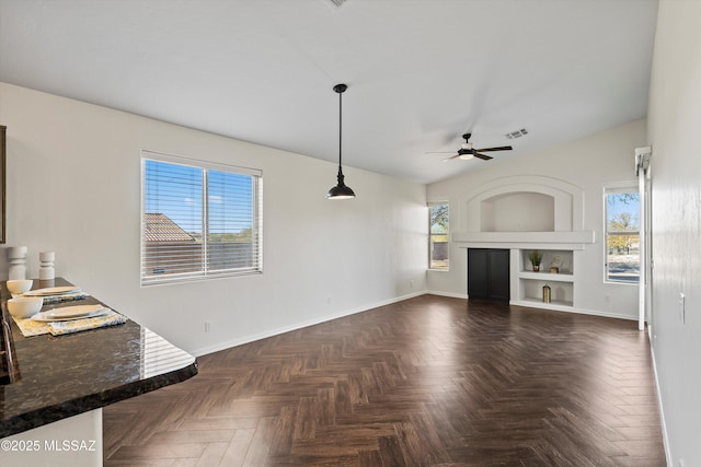 unfurnished living room with ceiling fan, built in features, and a healthy amount of sunlight