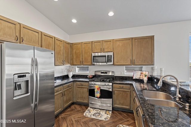 kitchen with dark stone countertops, appliances with stainless steel finishes, sink, and dark parquet flooring