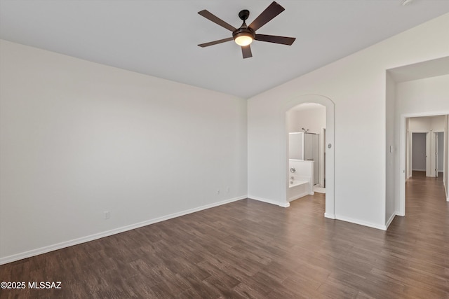 empty room with dark hardwood / wood-style flooring, vaulted ceiling, and ceiling fan