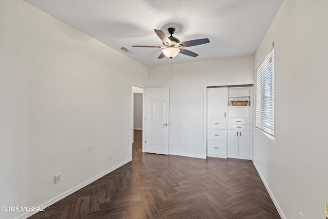 unfurnished bedroom featuring dark parquet flooring, a closet, and ceiling fan