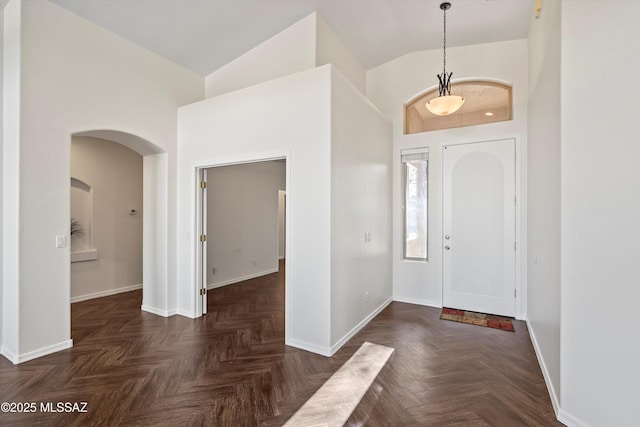 foyer with high vaulted ceiling and dark parquet floors