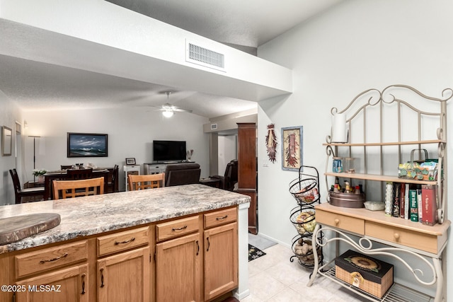 kitchen featuring vaulted ceiling, light stone countertops, ceiling fan, and light tile patterned floors