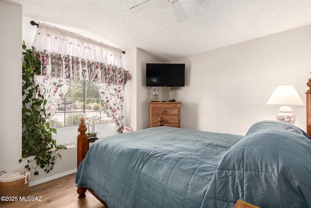 bedroom featuring ceiling fan, vaulted ceiling, a textured ceiling, and hardwood / wood-style flooring