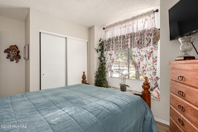 bedroom featuring lofted ceiling, hardwood / wood-style flooring, a textured ceiling, and a closet